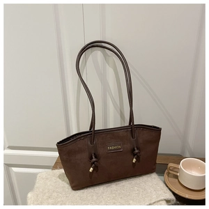 Détail du grand sac cabas en daim marron avec logo en métal et finitions nouées