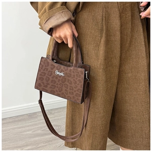 Détail du sac à main léopard avec logo argenté porté avec une tenue en velours