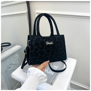Gros plan d'un sac à main noir à imprimé léopard avec texture en daim et logo
