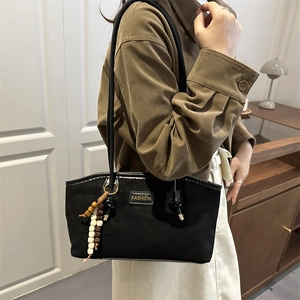 Grand sac fourre-tout noir rétro avec étiquette dorée et perles porté par un mannequin