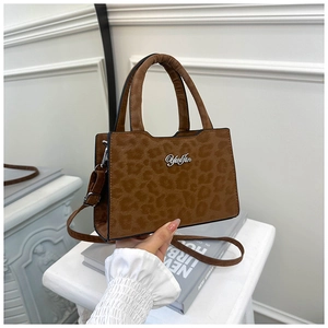 Détail d'un sac à bandoulière léopard avec texture mate et logo métallique doré