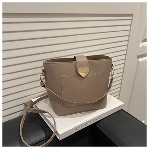 Detail of taupe leather bucket bag with gold heart clasp on a white book prop