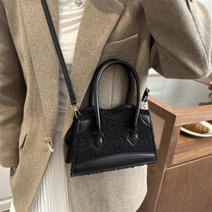 Chic black shearling tote bag with leather trim and shoulder strap in a lifestyle setting