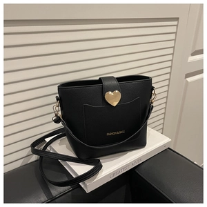 Detail of black lychee texture bucket bag with gold heart clasp and wide strap