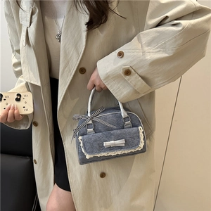 Sac à main rétro en denim gris avec dentelle et nœud, porté par un mannequin en trench