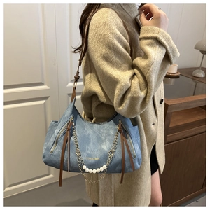 Detail of blue denim texture bag with white pearl chain and brown leather strap