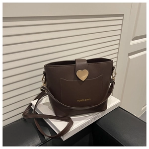 Detail of dark brown bucket bag with golden heart buckle and fine litchi texture