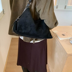 Detail of black faux suede hobo bag with contrast stitching on adjustable shoulder strap