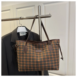 Detail shot of a large plaid tote bag with brown leather trim and stylish side drawstring