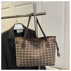 Detail of colorful plaid tote bag with dark brown straps and side drawstring on display