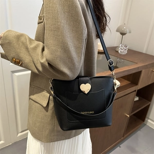 Minimalist black bucket bag with gold heart buckle and adjustable wide shoulder strap