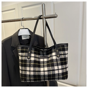Detail of checkered wool tote bag featuring black and yellow plaid with leather strap