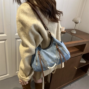 Retro denim hobo bag with pearl chain detail worn by model over a beige coat
