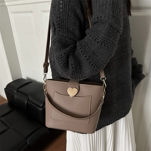 Chic brown bucket bag with gold heart clasp and wide strap for crossbody carry
