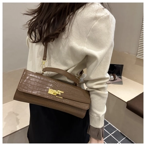 Close-up of brown crocodile pattern handbag with gold twist lock and elegant strap