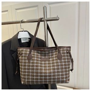 Macro detail of high-capacity wool plaid tote bag with brown leather shoulder straps
