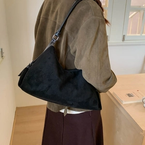 Retro black faux suede dumpling shoulder bag shown on model in a cozy interior setting