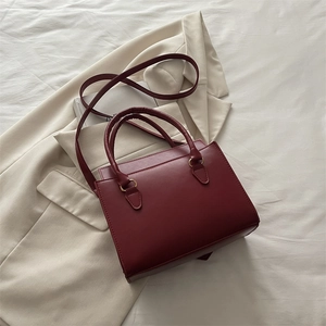 Sac à main bordeaux en cuir PU sur une veste beige avec des anneaux dorés élégants