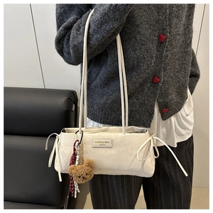 Dettaglio della borsa a spalla bianca con logo del marchio e ciondolo a forma di orsetto