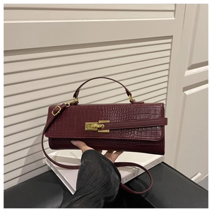 Close-up of wine red crocodile pattern handbag featuring a gold-toned twist lock closure