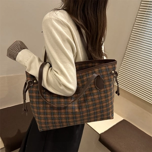 Brown and blue plaid large tote bag with leather straps on a model in warm indoor light