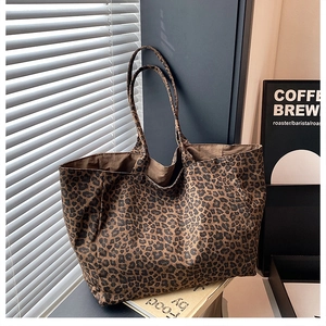 Detail view of large leopard print canvas tote bag with long shoulder straps and brown lining