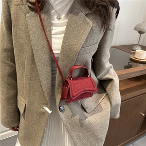 Petit sac bandoulière en daim bordeaux avec rabat ondulé dans un décor intérieur rétro