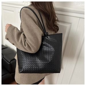 Detailed close-up of the black woven leather tote bag with elegant knot handle accents