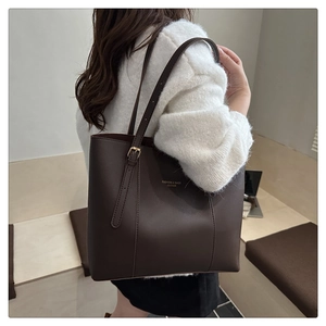 Detail of dark brown leather tote bag with gold lettering and adjustable shoulder strap