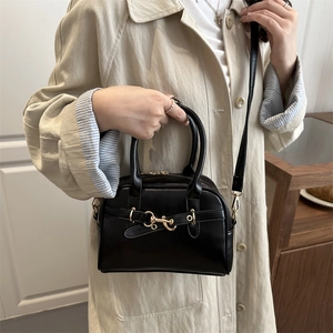 Retro oil wax leather Boston bag with gold buckle being worn with a beige trench coat