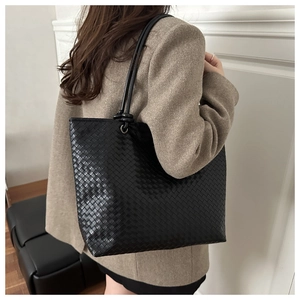 Detail shot of black woven leather tote bag with long shoulder straps for daily commute