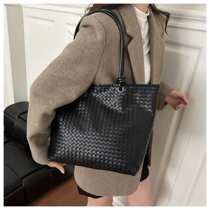 Detail of black woven leather tote bag showing intricate texture and silver metal buckle