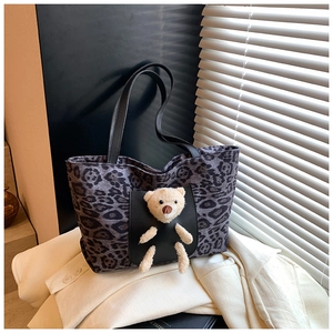 Close-up of leopard print tote bag featuring a 3D plush bear and black leather pocket