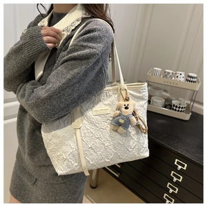 Vue détaillée du sac cabas blanc à broderies florales avec un charmant petit ours