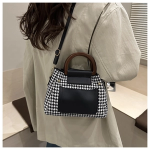 Detail of houndstooth crossbody bag with round wooden handle and black leather pocket