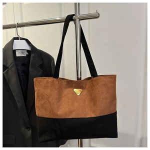 Detalle del bolso tote de ante con costuras en contraste y placa de logo triangular