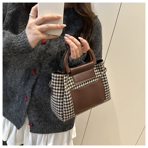 Detail view of houndstooth fabric handbag with premium leather handle and stitching