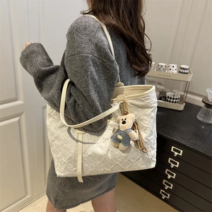 Borsa tote bianca trapuntata con ciondolo a orsetto indossata per un look trendy