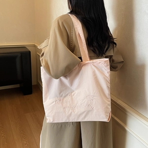 Minimalist light pink tote bag with embroidered heart patterns and wide shoulder strap