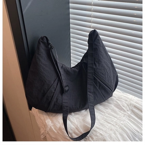 Detail of black nylon crossbody bag featuring waterproof pleated texture and adjustable strap