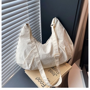 Detail of beige pleated crescent bag with adjustable wide strap and matte texture