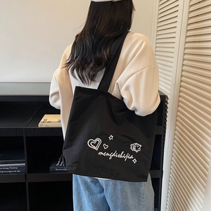 Black canvas tote bag featuring white heart embroidery for a minimalist casual style