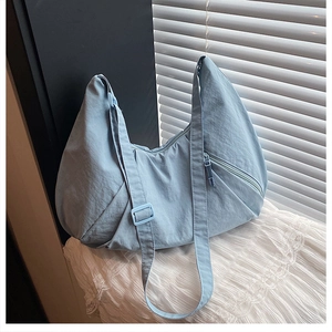 Detail of light blue crescent nylon bag with adjustable strap on a lace fabric