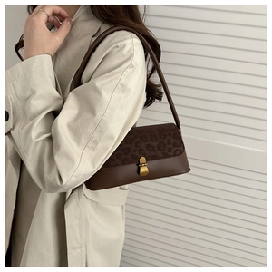 Close-up of leopard print baguette bag with golden metal buckle on beige trench coat