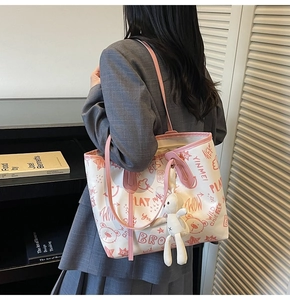 Close-up of white canvas tote bag with pink graffiti bear print and bunny plush charm