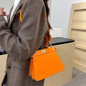 Elegante borsa a mano arancione con trama coccodrillo e chiusura dorata con blazer in tweed
