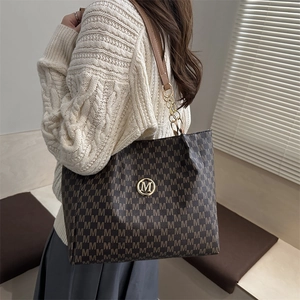 Sac cabas classique marron foncé avec motif M et chaîne dorée porté par un mannequin