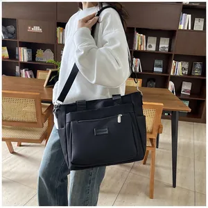 Detailed side view of black nylon multi-pocket tote bag with adjustable shoulder strap