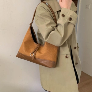 Fashionable brown nubuck leather shoulder bag with decorative metal ring in a stylish pose