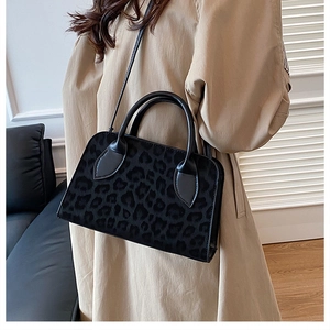 Détail du sac à main noir à motif léopard avec poignées rondes et bandoulière en cuir